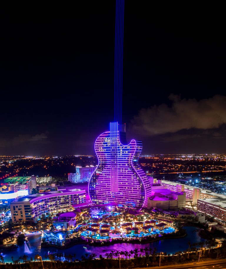 Aerial view of the Hard Rock Guitar Hotel lit up at night, by Arte City Media