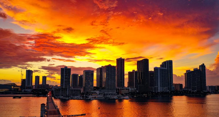 Miami skyline silhouetted against a fiery sunset over Biscayne Bay, by Arte City Media