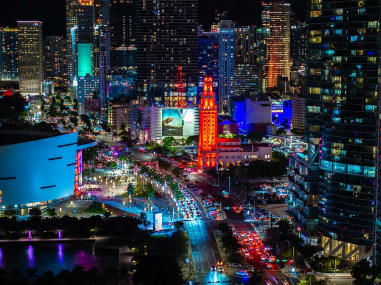 Aerial view of downtown Miami at night with the Freedom Tower lit up, by Arte City Media