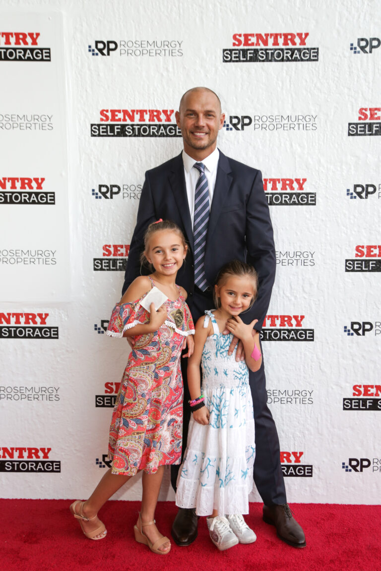 Father and his two daughters at a red carpet step-and-repeat, by Arte City Media
