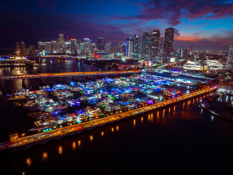 Aerial view of a lighted boat parade on Biscayne Bay at night, by Arte City Media
