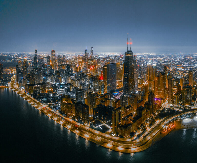 Aerial view of the Chicago skyline at night along Lake Michigan, by Arte City Media