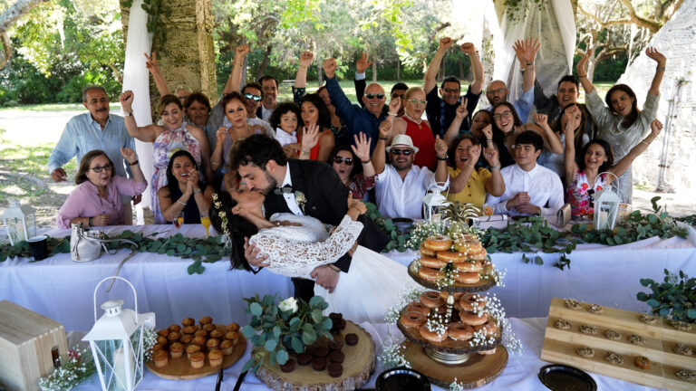 Couple kissing as family and friends cheer at a milestone celebration, by Arte City Media