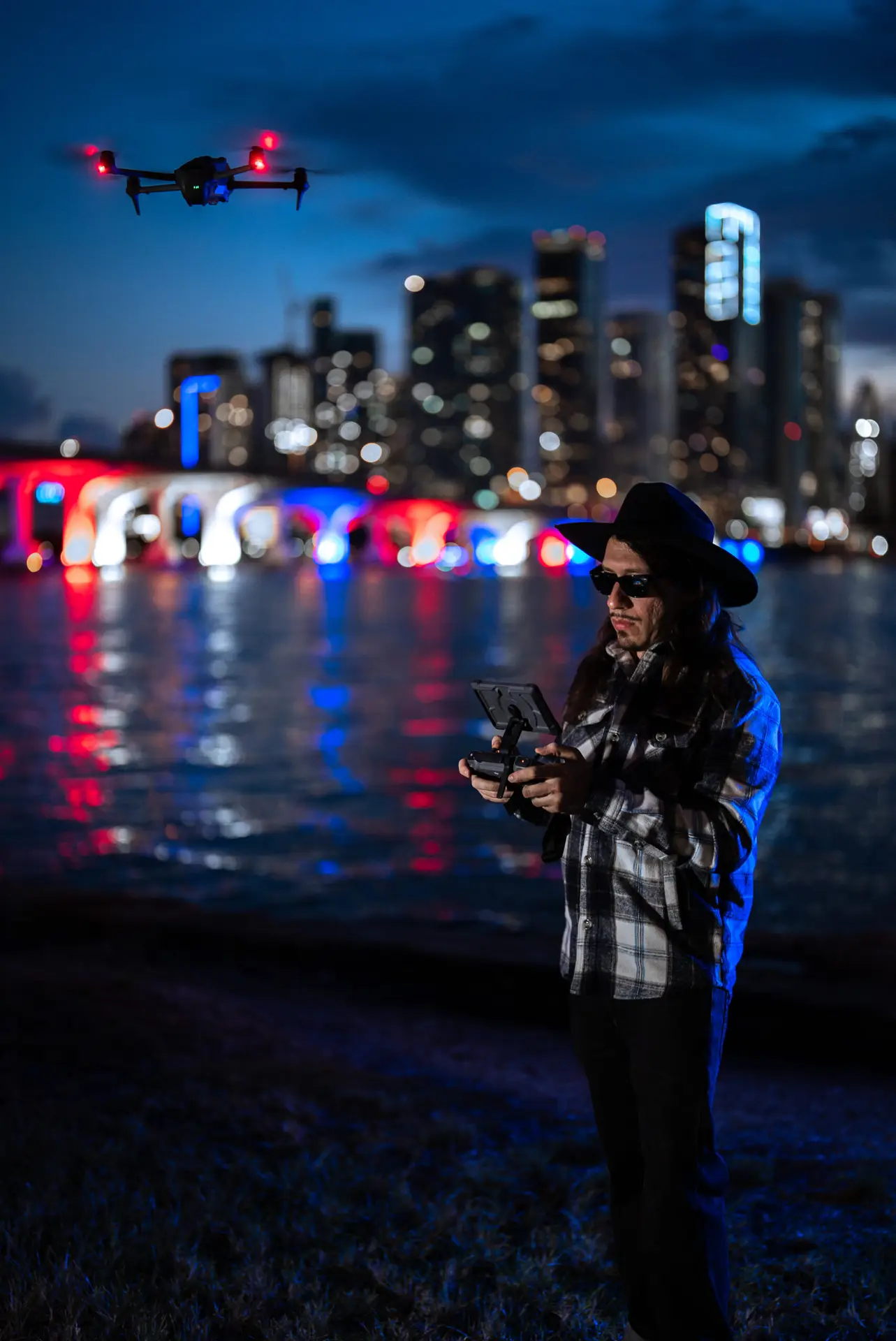 Matthew Hoyos flying a drone at night in front of the Miami skyline