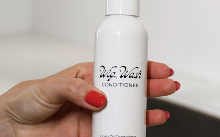 Hand holding a Wig Wash conditioner bottle from a commercial product shoot