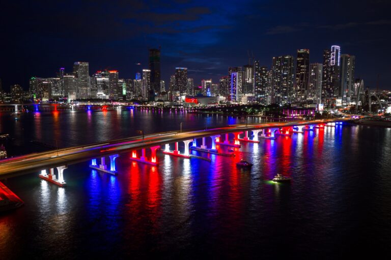 Downtown Miami skyline at night with bridge lights reflecting on Biscayne Bay