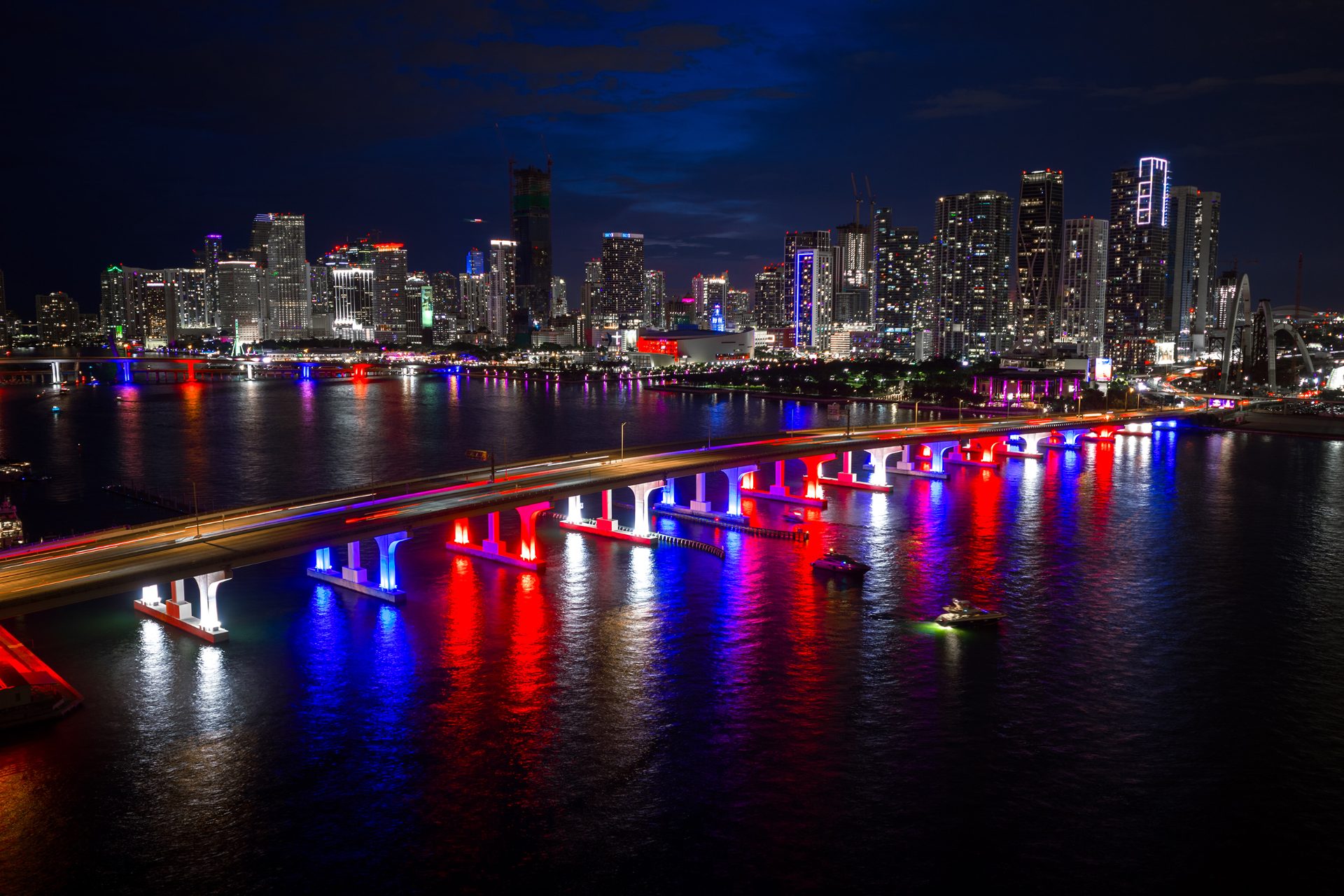 Downtown Miami skyline at night with bridge lights reflecting on Biscayne Bay