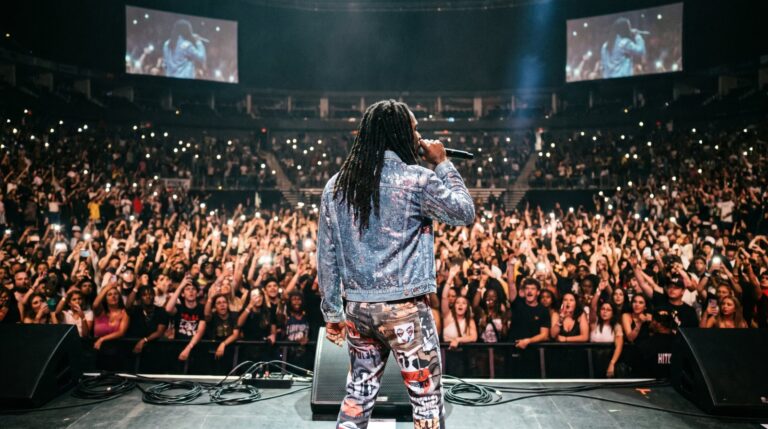 Artist performing on stage to a packed arena crowd, event photography by Arte City Media