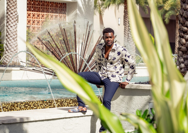 Creative editorial portrait of a man in a floral shirt by a fountain, by Arte City Media
