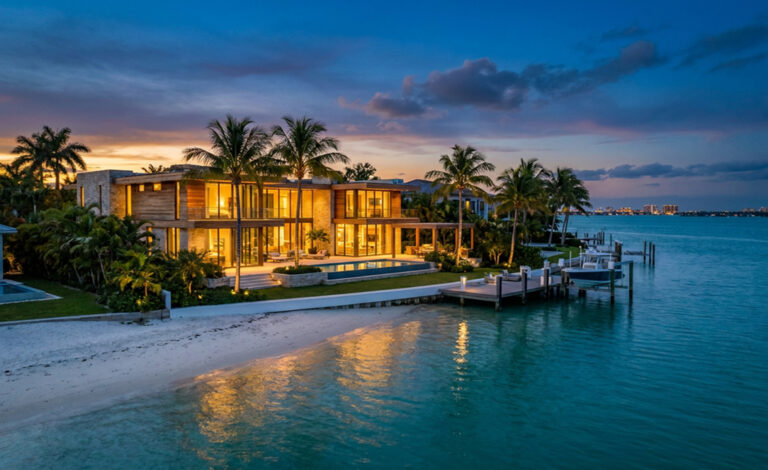 Aerial view of a waterfront mansion with a pool and dock glowing at dusk, by Arte City Media